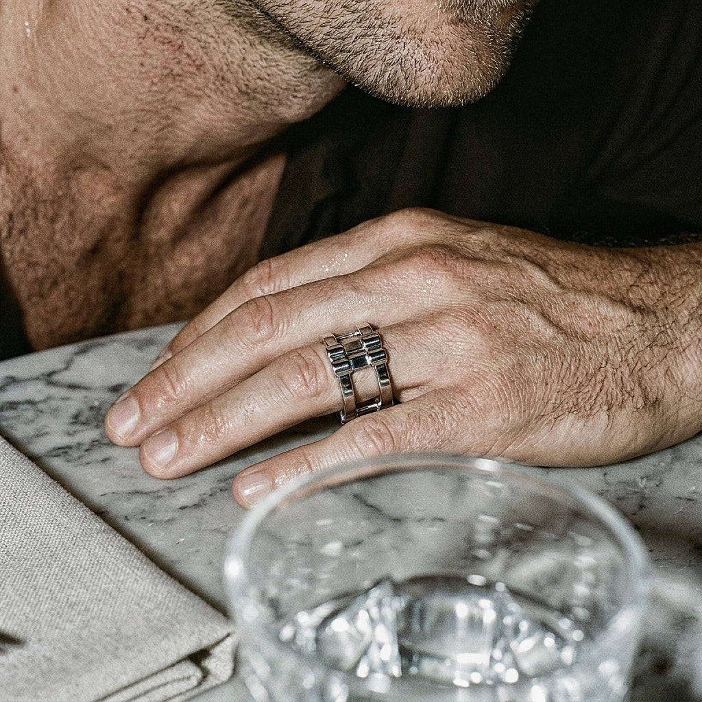 Wide band silver ring on male hand, marble surface lifestyle shot