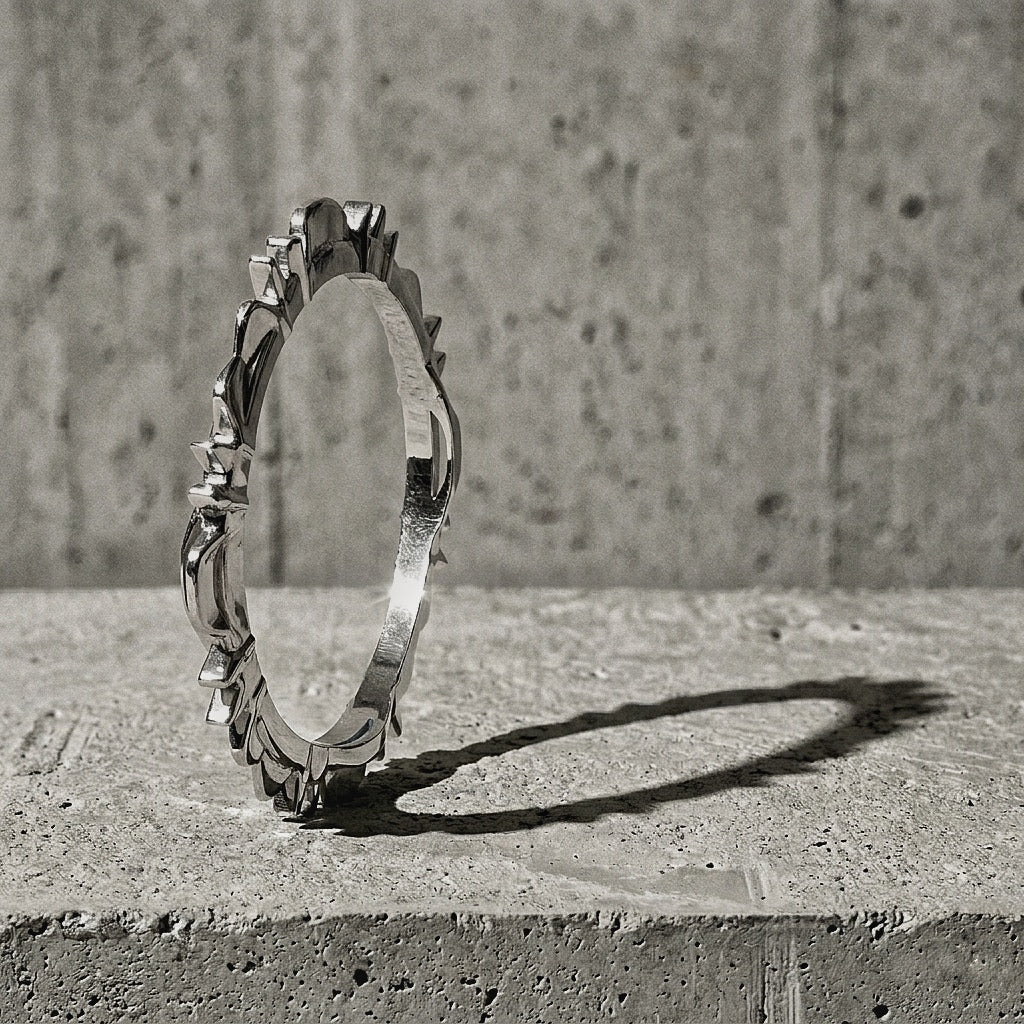 Sculptural closed bangle standing upright on concrete with continuous perimeter ridge of peaks visible, A Gross Domestic Product