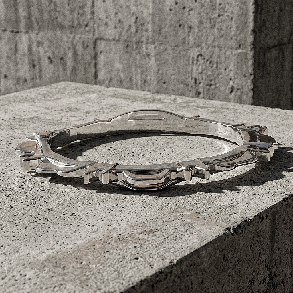 Heavy sterling silver bangle resting on concrete revealing the smooth interior band beneath the ridged exterior