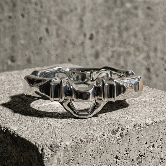 Sculptural ring with undulating band and architectural crown composition on concrete, A Gross Domestic Product