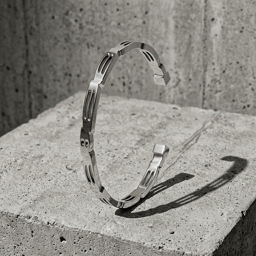 Slim sculptural cuff with pierced oval reliefs and stepped upper edge upright on concrete pedestal, A Gross Domestic Product