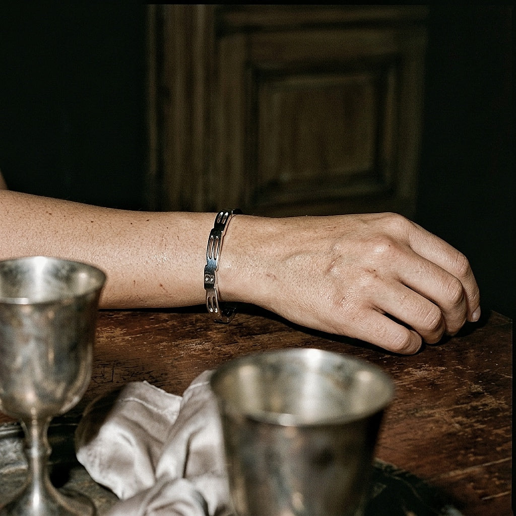 Slim sterling silver cuff on forearm at table with vintage silver chalices and white linen, Renaissance-domestic editorial light