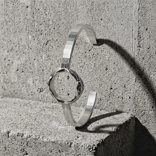 Twin-band sculptural cuff with Spiked module visible on front face on concrete surface, A Gross Domestic Product